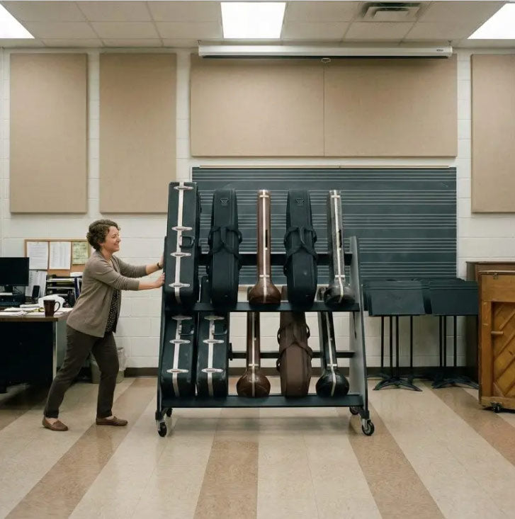 Person pushing a cart with musical instruments in a room with beige walls and a desk.