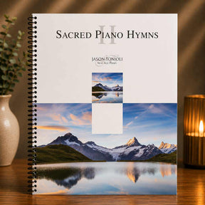 Book titled 'Sacred Piano Hymns II' by Jason Toniolli with mountain and lake cover design on a wooden surface.